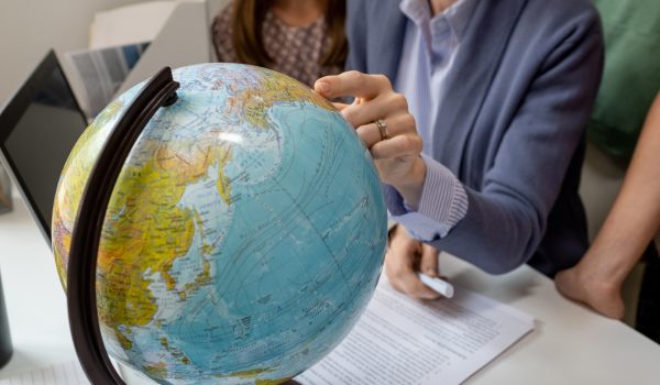 Hand of geography teacher pointing at continent on globe during lesson